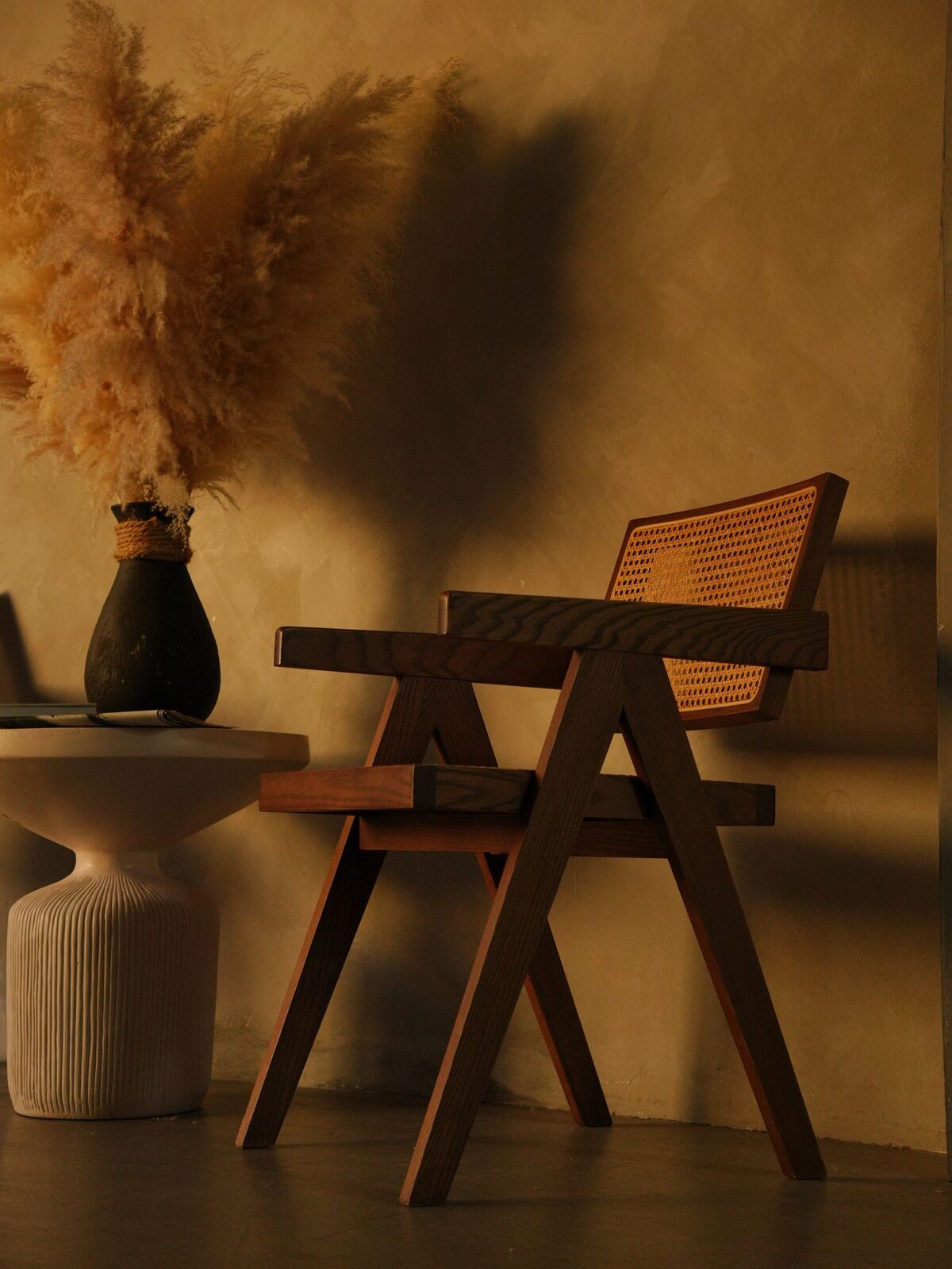 A stylish corner of Villa Amara with a rattan chair and a spray of dried pampas grass