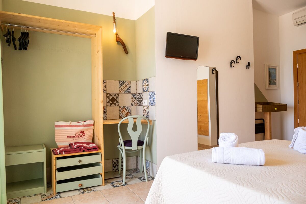 A light twin bedroom with patterned floor tiles and crisp white bedding